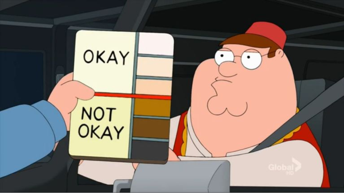 Peter Griffin from Family guy in a red fez. In front of him an officer holds up a skin color chart, with lighter hues being marked "Okay", and darker tones "Not okay"