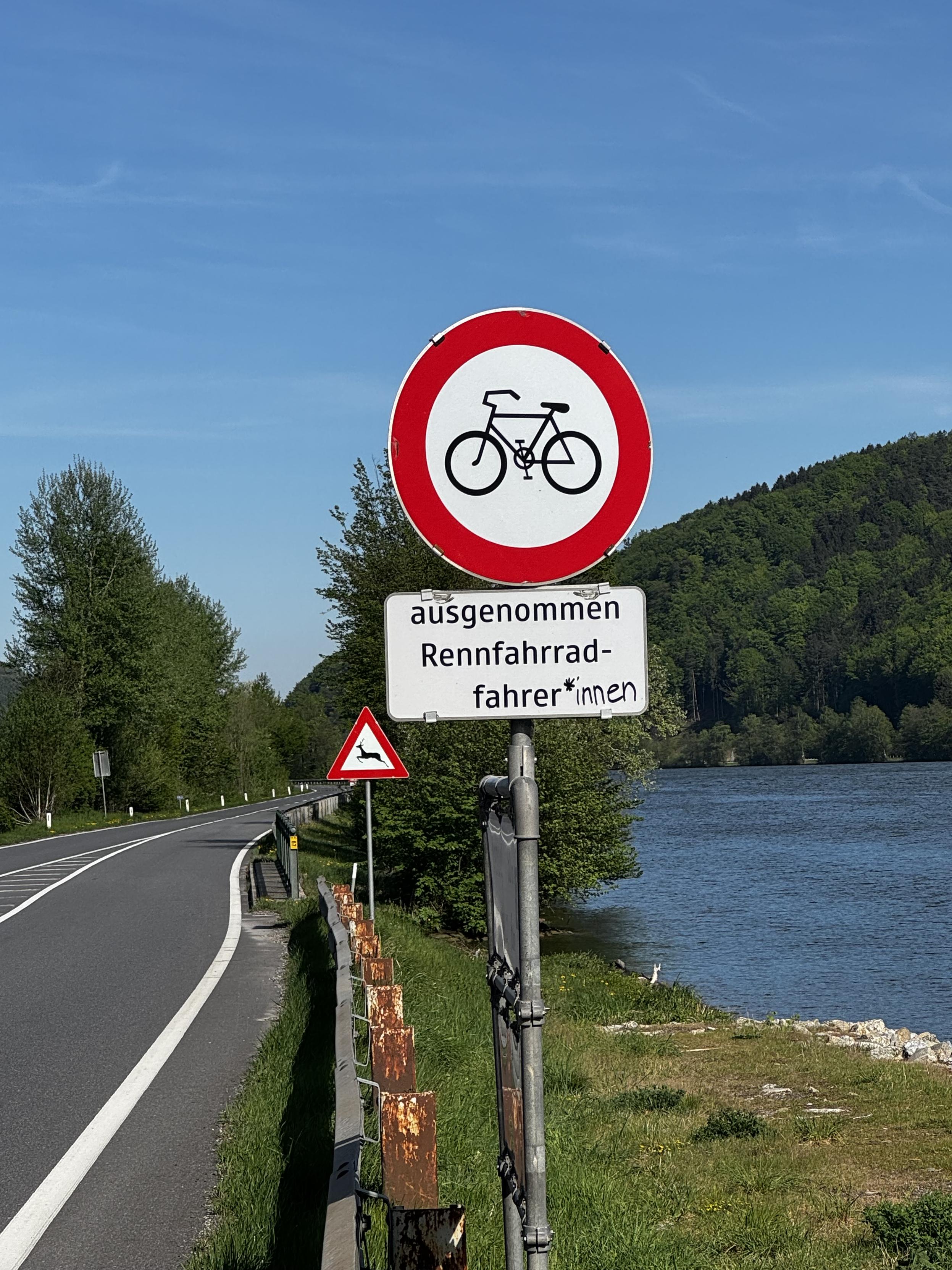 Schild: Radfahren verboten mit dem Zusatz „Ausgenommen Rennradfahrer(*innen)“