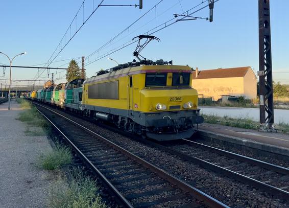 A yellow SNCF Infra Bb22200 hauls half a dozen diesel locomotives through Nuits 